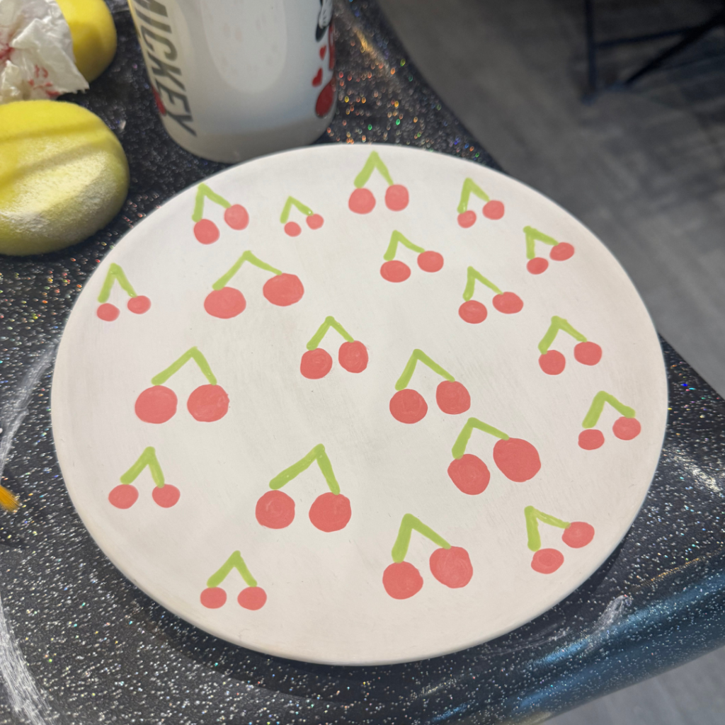 A plate with painted cherries on